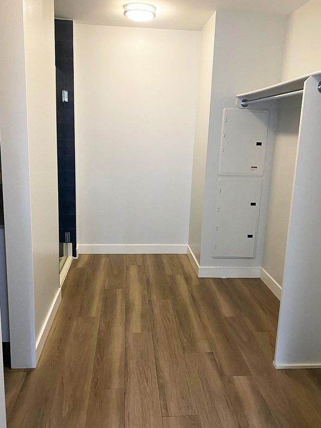 An empty closet with a clean floor, shelf and hanging rail