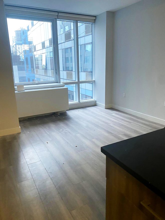 An empty living area with floor-to-ceiling windows and a clean plank floor