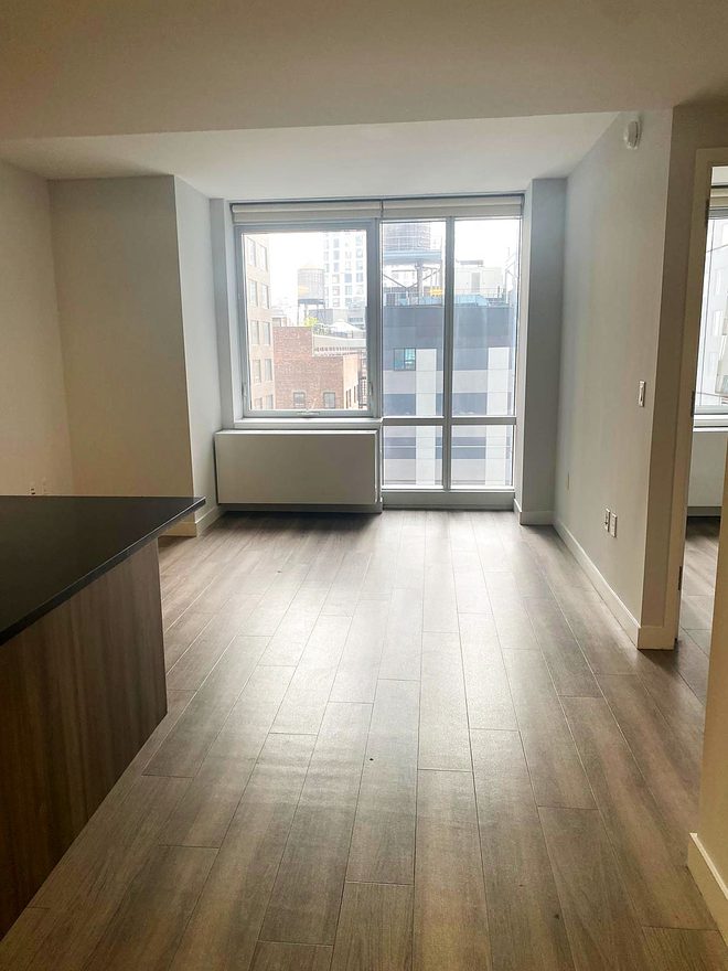 A wide view of a cleaned studio with counter, plank floor and window wall